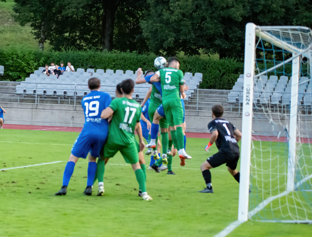 Mehrere Männer spielen vor Fußballtor mit Ball