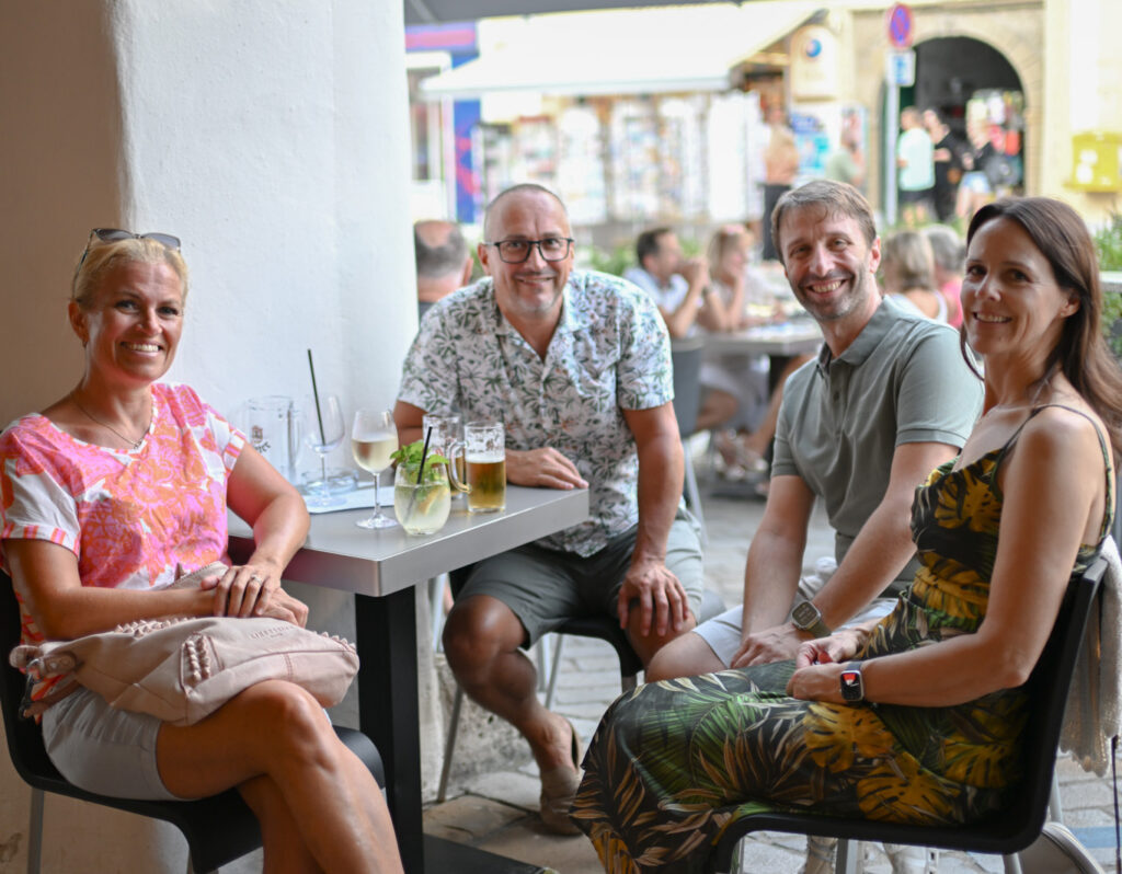 Personen sitzen am Sessel und stützen sich mit Ellbogen am Tisch ab