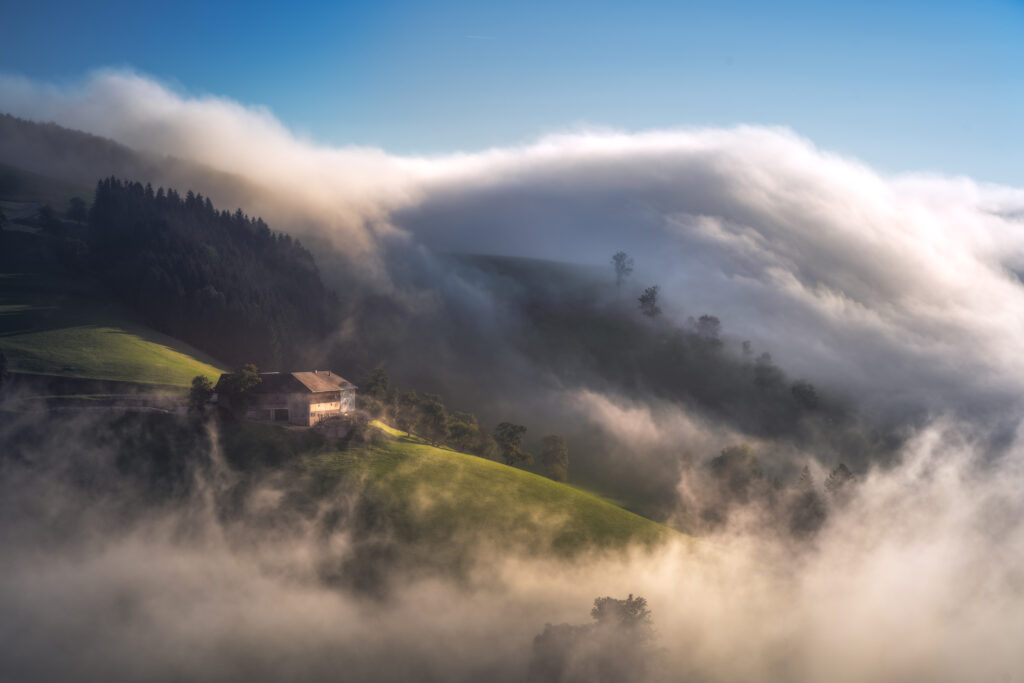 Nebel zieht bei Sonnenschein über Berg herunter