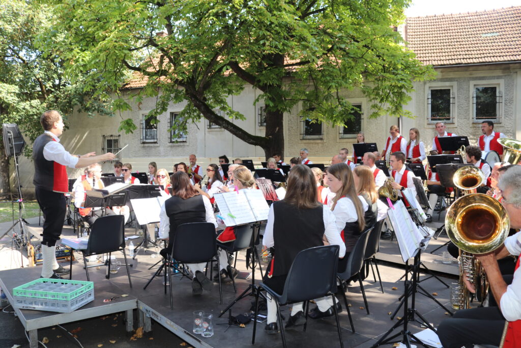 Musikkapelle spielt auf Podest unterm Baum